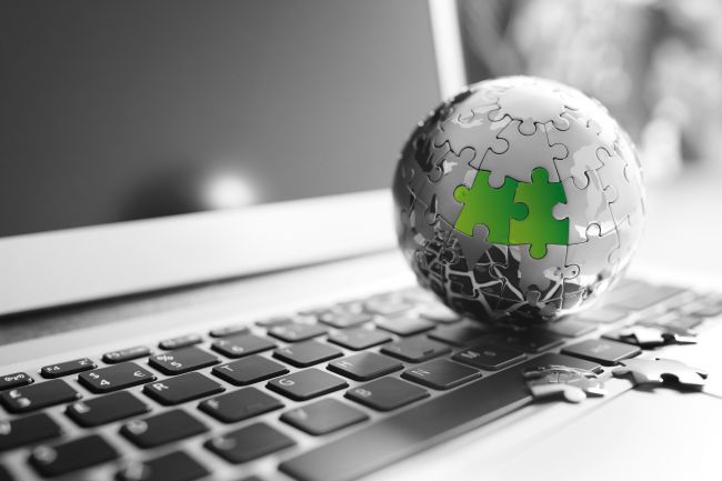 Globe made out of puzzle pieces next to laptop